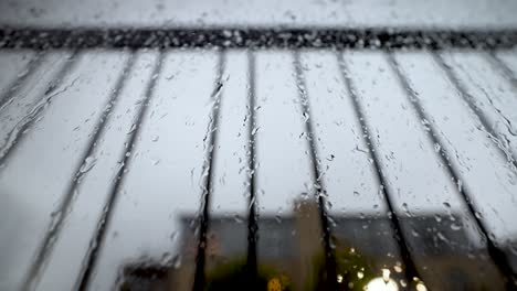 Close-Up-View-Looking-Up-At-Window-Covered-In-Rain-Droplets-Behind-Safety-Bar