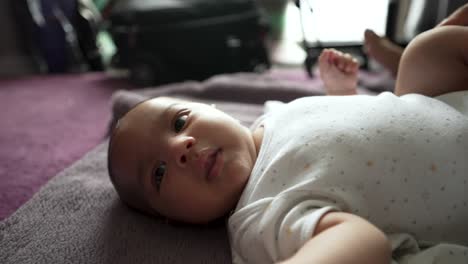 Entzückender-2-Monate-Alter-Indischer-Junge,-Der-Auf-Einer-Decke-Auf-Dem-Boden-Liegt-Und-Sich-Von-Den-Eltern-Anzieht