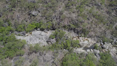 Emerald-Creek-Falls-Surrounded-With-Granite-Boulders-And-Green-Vegetation-In-Mareeba,-Australia---aerial-drone-shot