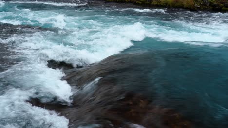 Close-up-shot-of-turbulent-crashing-river-flowing-downhill-the-mountain-in-Iceland