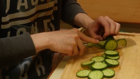 a-young-man-cuts-a-cucumber-with-a-knife-for-a-salad