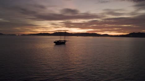 Slowmotion-shot-of-an-anchored-boat-in-the-ocean-off-the-coast-of-Malaysia-with-the-sun-setting-behind