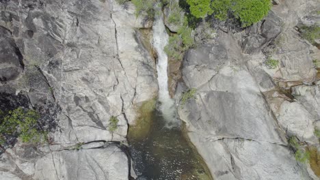 Water-Cascading-Down-Rocks-At-Emerald-Creek-Falls-In-Mareeba,-Australia---aerial-drone-shot