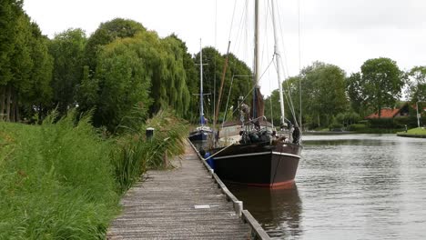 Segelboot-Vor-Anker-Von-Holzsteg-Im-Kanal