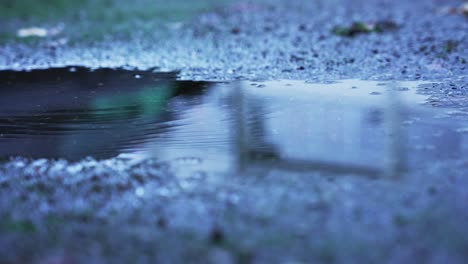 Multiple-small-water-drops-falling-in-a-puddle-on-the-concrete