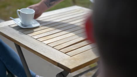 Person-Placing-Empty-Coffee-Cups-With-Saucer-In-A-Wooden-Table-Outdoor