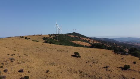 Spinning-windmills-generating-green-energy-on-Spanish-soil,-aerial-descend-view