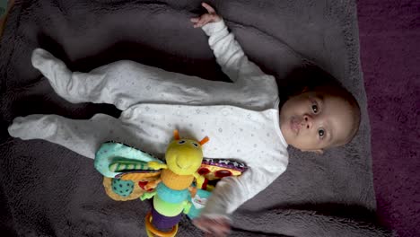Top-Down-View-Of-Cute-2-Month-Old-Indian-Baby-Boy-Laying-On-Blanket-With-Stuffed-Toy-By-Side-And-Wriggling
