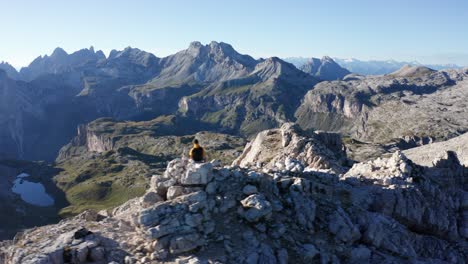 Mountain-climber-sitting-on-top-of-the-mountain,-Dolomites-aerial-landscape