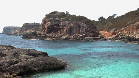 Wide-shot-of-rocky-coastline-and-cliffs-with-turquoise-colored-water-at-Caló-des-Moro-Bay-on-Mallorca-Island