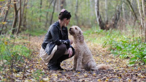 Goldendoodle-kissing-and-licking-woman-in-the-woods-while-sitting
