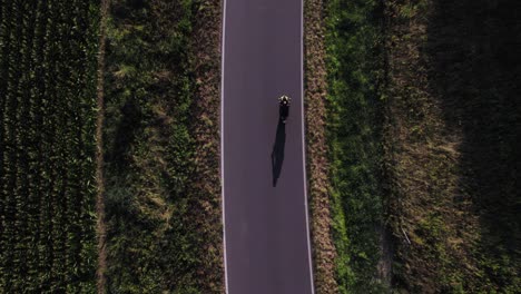Man-Driving-Modern-Sport-Motorcycle-on-Countryside-Asphalt-Road-at-Sunset---Top-down-view-from-drone