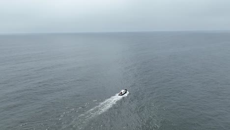 Aerial-drone-shot-of-the-pacific-ocean-in-the-sea-of-peruwith-calm-sea-on-which-a-boat-floats-out-to-sea