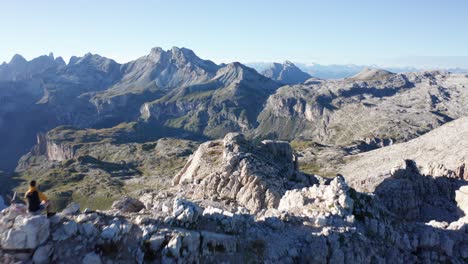 Mountaineer-sitting-on-mountain-peak-in-Dolomites,-aerial-push-in