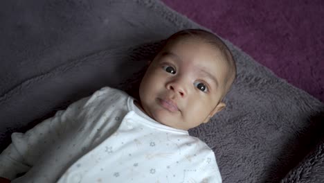 Adorable-2-Month-Old-Indian-Baby-Boy-Looking-Doughy-Eyed-At-Camera-Whilst-Laying-On-Blanket-On-The-Floor