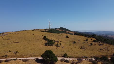 Row-of-windmill-producing-electricity-in-Spain,-aerial-reveal-fly-away-view