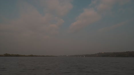 Weitwinkelaufnahme-Eines-Sees-Auf-Einem-Boot,-Das-über-Den-See-Segelt,-Mit-Blick-Auf-Ruhiges-Wasser,-Bäume-Und-Wolken-Am-Himmel