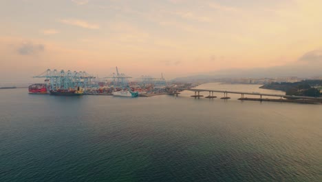 dolly-out-drone-shot-of-of-Algeciras-port,-close-to-the-container-terminal-with-the-view-of-the-bridge-for-delivery-containers-to-port