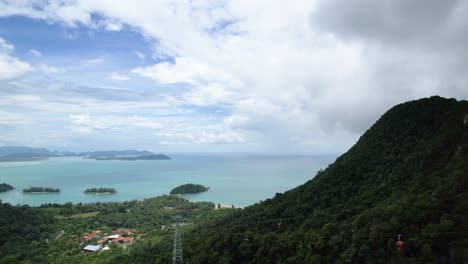 Panorama-Del-Océano-Azul-Tranquilo-Con-Vistas-A-Los-Teleféricos-Que-Se-Mueven-Sobre-Montañas-Exuberantes-En-La-Isla-De-Langkawi,-Malasia