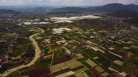 Agriculture-field-plots-and-rural-village-in-Vietnam,-aerial-drone-view