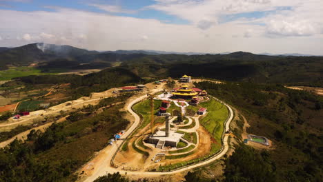 Majestic-pagoda-temple-under-construction-with-heavy-equipment,-aerial-drone-view