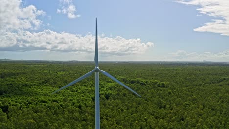Aerial-dolly-out-reveals-wind-turbines-in-lush-landscape,-blue-sky-with-clouds