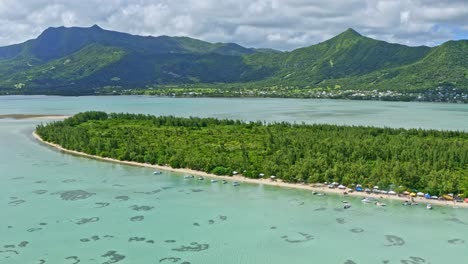 Aerial-Drone-Above-Coral-Reef-of-Mauritius-Islands-Blue-lagoon,-Boats,-Sea-Life-and-Green-Mountains-with-a-Cloudy-Blue-Sky,-Crystalline-Water