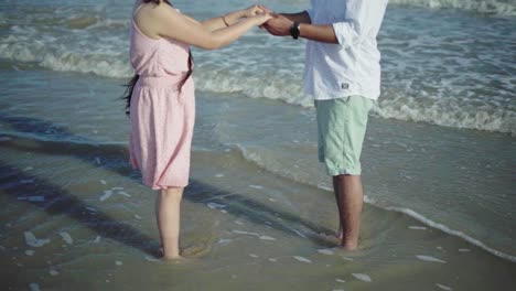 Without-face-shot-of-a-couple-holding-hands-and-playing-near-the-waves-in-a-beach