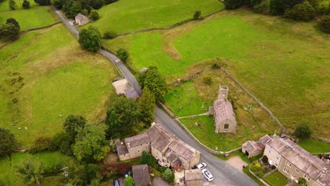 Drone-aerial-view-looking-down-at-Yorkshire-village-and-church-and-natural-green-landscape