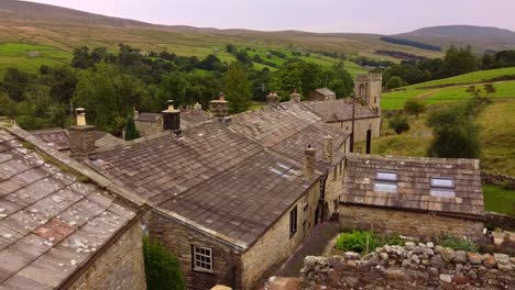 Drone-aerial-reveal-across-old-stone-cottage-roof-across-Yorkshire-Dales-valley