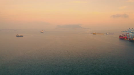 Container-ships-travelling-across-Mediterranean-sunrise-sea-towards-Port-of-Algeciras-international-shipping-terminal