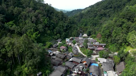 Secret-hidden-village-deep-inside-lush-green-jungle,-drone-view
