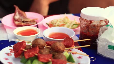 Close-up-to-a-plate-full-of-deep-fried-khmer-street-food-skewers-being-eaten-by-a-tourist