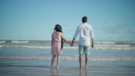 Slow-motion-shot-of-a-couple-in-a-beach-standing-and-watching-the-beautiful-waves