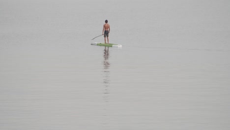 Young-fit-man-moves-effortless-in-a-paddle-board-in-calm-sea-at-sunrise-in-slow-motion-60fps