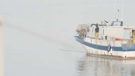 Kleines-Fischerboot,-Das-Fischernetz-Mit-Zwei-Arbeitern-In-Ruhiger-See-Bei-Sonnenaufgang-In-Zeitlupe-60fps-Sammelt