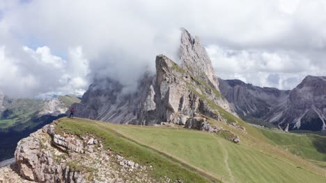 Person-Auf-Bergspitze-Fliegende-Drohne-Filmt-Epische-Bergkette-Nach-Wanderung-Seceda-Ridgeline-Track-In-Den-Dolomiten,-Italien