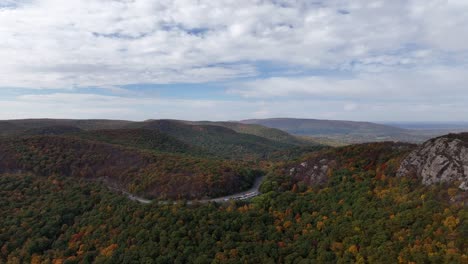 An-aerial-view-high-over-the-mountains-in-upstate-NY-during-the-fall-foliage-change,-on-a-beautiful-day-with-white-clouds
