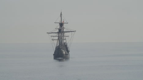 Ferdinand-Magellan-Nao-Victoria-carrack-boat-replica-with-spanish-flag-sails-in-the-mediterranean-at-sunrise-in-calm-sea-front-shot-in-slow-motion-60fps