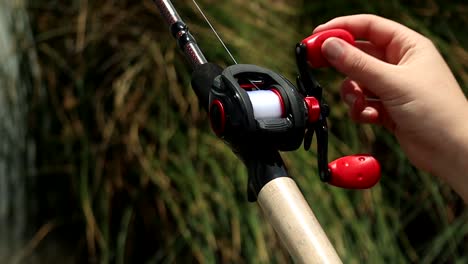 Close-Up-shot-of-Hands-reeling-in-a-Bass-Fishing-Reel