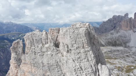 Mountaineer-climbing-steep-mountain-peak-in-Dolomites,-Torre-di-Toblin-aerial-orbit,-at-Tre-Cime