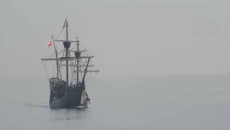 Ferdinand-Magellan-Nao-Victoria-carrack-boat-replica-with-spanish-flag-sails-in-the-mediterranean-at-sunrise-in-calm-sea-front-shot-in-slow-motion-60fps