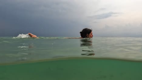 Half-underwater-view-of-adult-caucasian-woman-crossing-scene-swimming