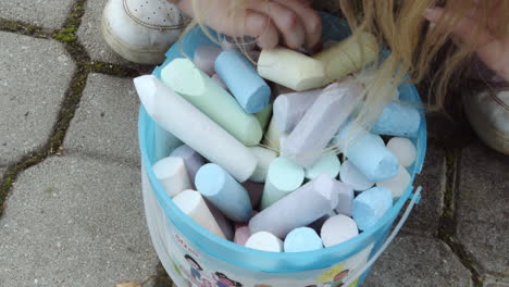 Child's-hand-looking-for-the-right-colour-in-a-bucket-of-chalk-Close-up-shot