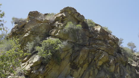 Panning-shot-through-a-ravine-in-a-rocky-hillside-on-a-sunny-day-in-Santa-Paula-Punch-Bowls-Southern-California
