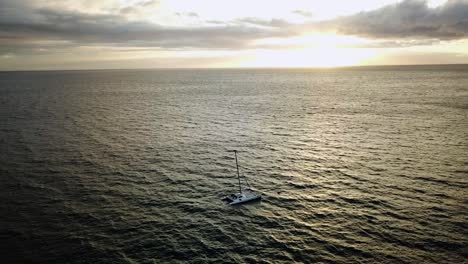 Vista-Aérea-Del-Catamarán-En-El-Océano-Pacífico,-Durante-La-Puesta-De-Sol---Seguimiento,-Disparo-De-Drones