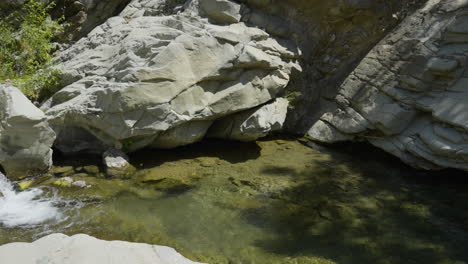 Panning-shot-of-small-waterfall-running-into-creek-located-in-Santa-Paula-Punch-Bowls-Southern-California