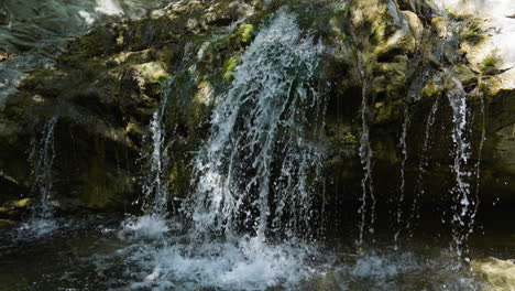 Descending-shot-of-small-waterfall-running-into-creek-below-located-in-Santa-Paula-Punch-Bowls-Southern-California