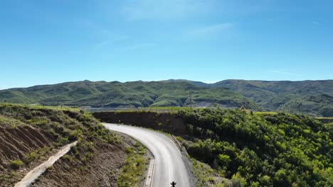 Biker-riding-alone-on-an-empty-road-in-the-hills-during-daylight