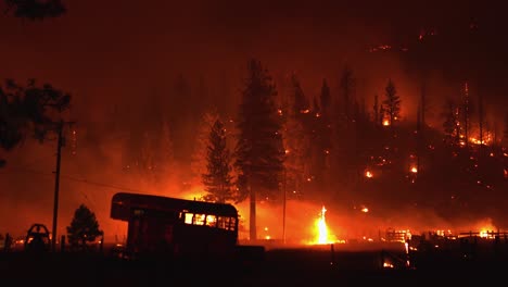 Ranch-burning-in-middle-of-glowing-red,-smoky-wildfire-forest-in-western-USA
